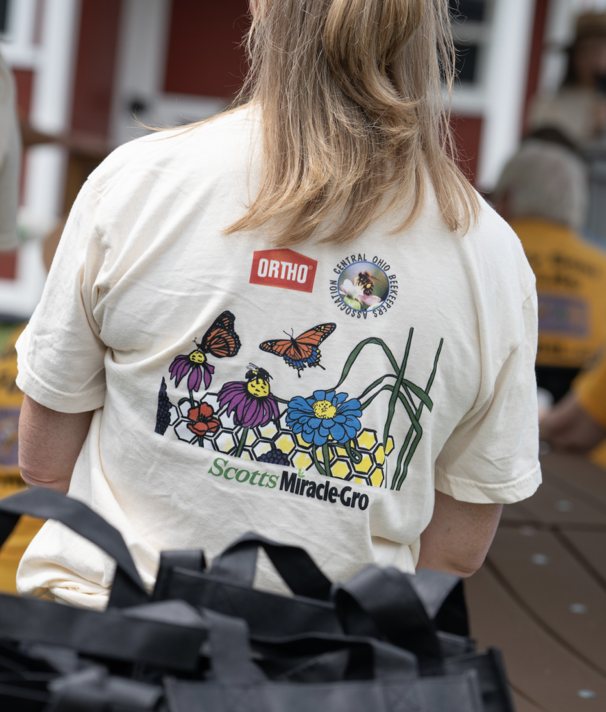 Close-up of a t-shirt featuring butterflies, the Ortho logo and the logo for ScottsMiracle-Gro's new Apiary